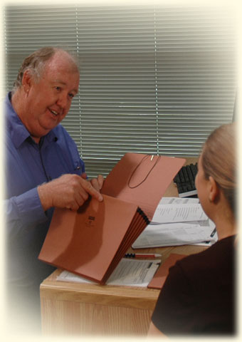 Scobie and the SAA Rep sitting at his desk looking at paperwork.